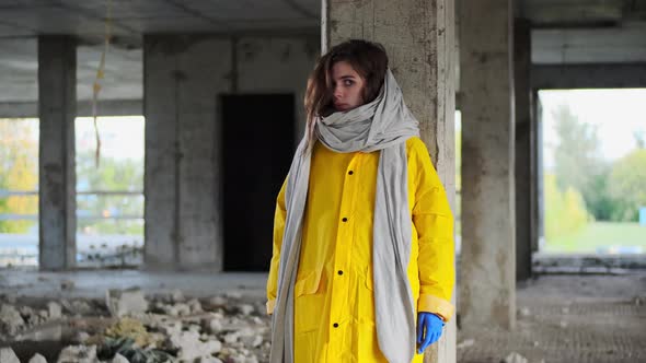 Beautiful Lonely Longhaired Woman in Yellow Raincoat and Blue Gloves Turns Her Head to Camera Stands