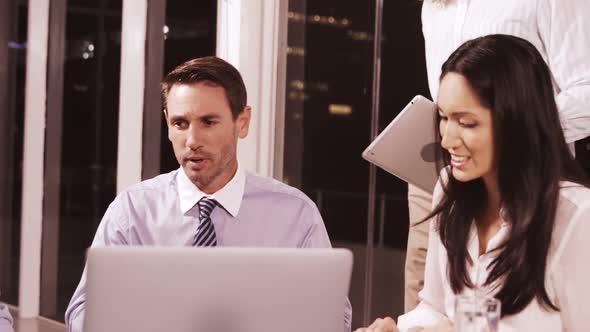 Businesswoman discussing with colleagues over laptop