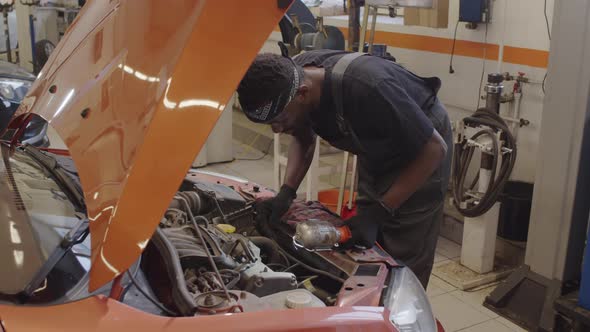 African American Mechanic Checking Car Parts in Auto Repair Shop