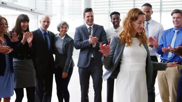 Businesswoman dancing while her colleagues applauding