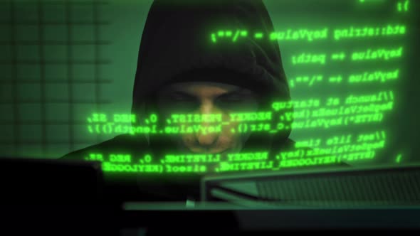 Close-up of Male Hacker Working on a Computer for Cyber Attack While Green Binary Hacking Code