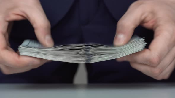 Man Touches Holds and Counts a Stack of 100 American Dollars Money