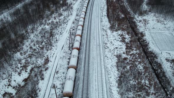 Camera Panning Up Slow Aerial Flight Over Stationary Cistern Tank Train Covered in Snow During