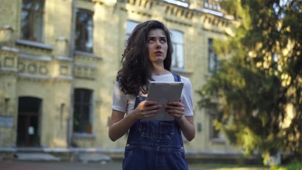 Intelligent Young Woman Studying Homework with Tablet Crossing Fingers Getting Ready for an Exam