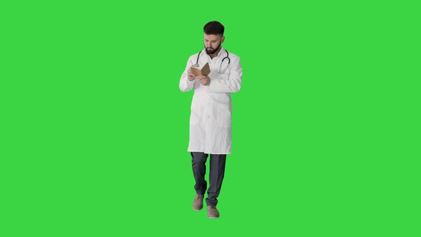 Walking Doctor or Medic Man Holding Pen and Notebook Looking for Idea on a Green Screen, Chroma Key.