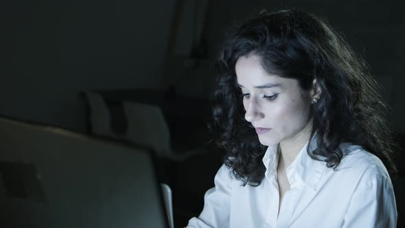 Focused Businesswoman Using Computer in Dark Office