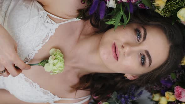 A Vertical Shot of a Girl Who Lies in Colorful Fresh Flowers