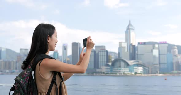 Woman taking photo on Victoria harbor in Hong Kong 