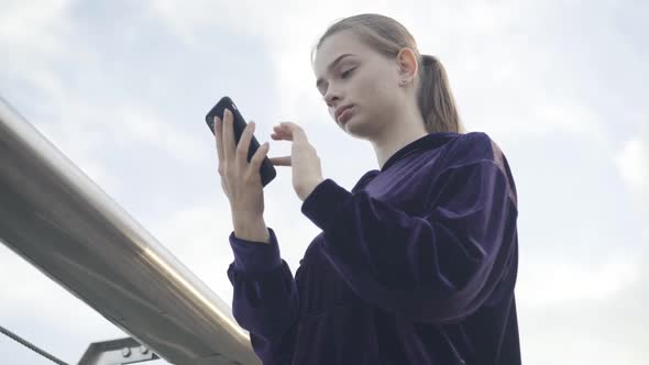 Bottom View of Young Surprised Woman Looking at Smartphone Screen and Gasping