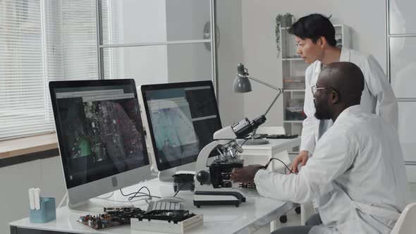 Diverse Engineers Working with Microscope in Laboratory