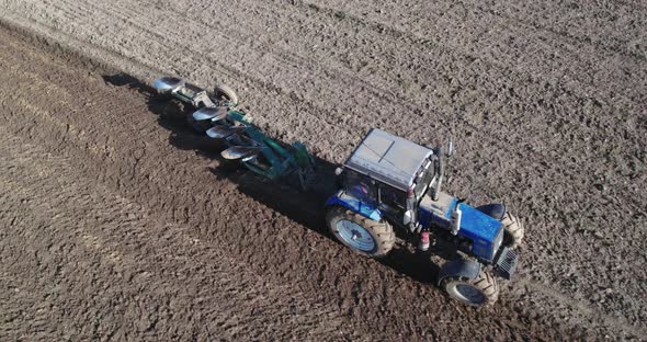 Tractor with a Trailed Plow Cultivating the Soil in Season