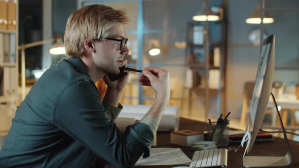 Architect Talking on Phone and Working on Computer in Night Office