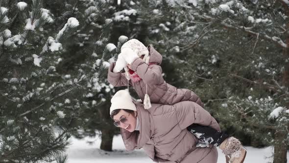 Mother Have Fun with Daughter in Winter Forest Playing with Snow