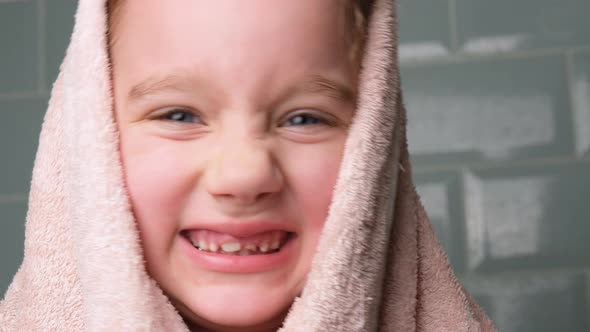 Portrait of Cheerful Little Girl Wrapped in Bath Towel and Looking in Camera