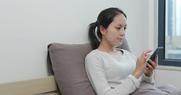 Woman Use of Cellphone and Apply Paper Mask on Face at Home