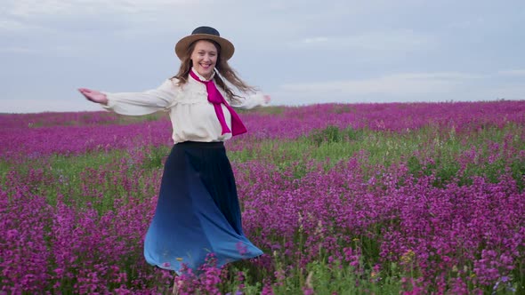 Girl in a Blue Dress with a White Blouse and a Straw Hat Walks Along