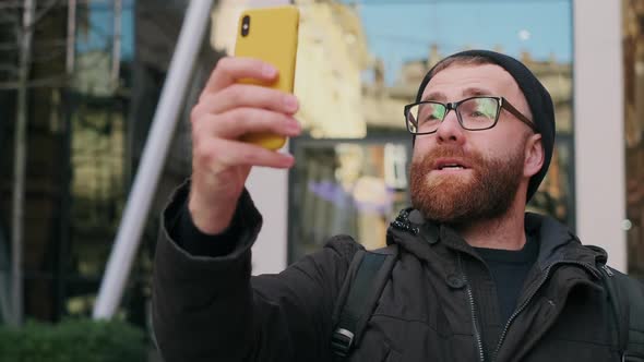 Handsome Man in Glasses Having Video Call or Making Message While Looking at Screen. Bearded Guy