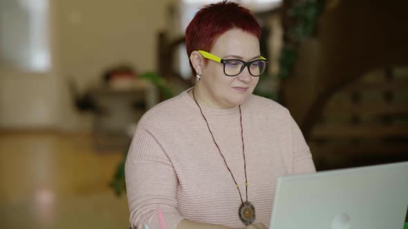 Middle Aged Woman with Glasses Typing Text on Laptop at Home Serious Focused