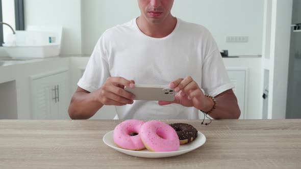 Close Up Food Photographer Take Pictures with Smartphone of Colored Fresh Donuts in Plate on Kitchen