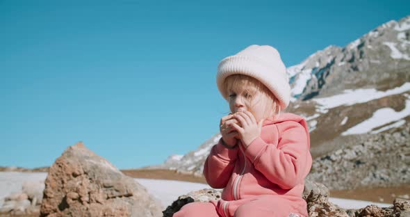 Cute Toddler Girl Sit and Eat Apple on Epic Mountain View