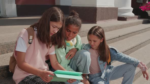 Girls Using Tablet on Steps of School Building