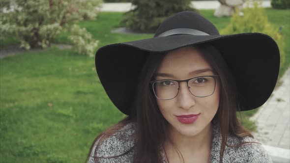 Close Up Portrait of Pretty Smiling Woman in Black Hat and Glasses in the Park
