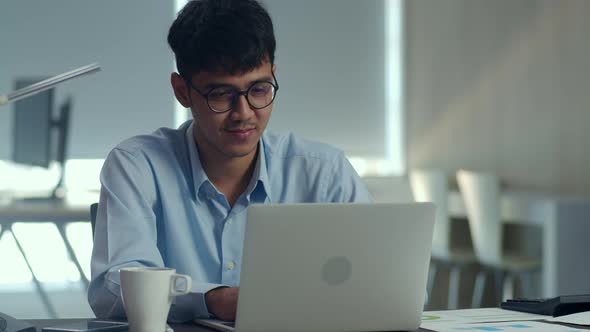 Young professional business male using computer looking information paper at office.