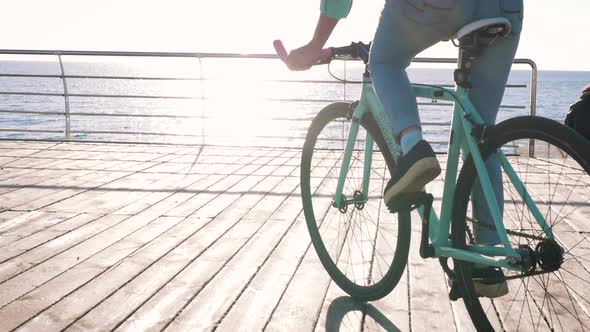 Young Stylish Woman Cyclist Enjoying Fixed Gear Bike Riding Outdoors at Sunrise Near the Sea Close