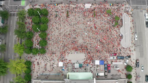 Aerial Descending Shot Above a Crowd of Protesters in Orange Shirts. Wide daytime exterior overhead