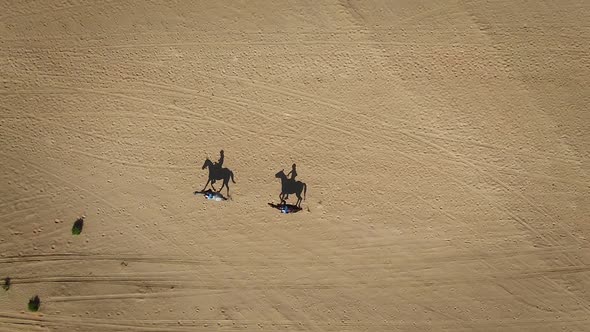 Aerial view of people riding horses in the desert of Al Khatim in Abu Dhabi.