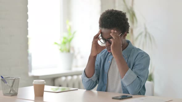 Young African Man Having Headache While Sitting at Work