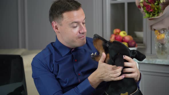 Young Man is Working From Home with His Computer in Office and His Dog Distracts Him