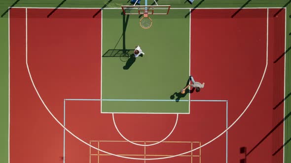 Aerial View of Two Young Male Friends Playing Basketball on Court Outdoors