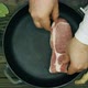 The cook puts the meat on the pan. Sliced pork steaks in a cast iron skillet. A metal frying pan - VideoHive Item for Sale