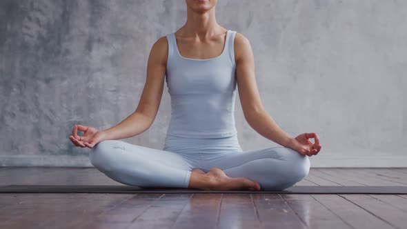 Young and sporty girl in sportswear is doing yoga exercises in home interior.