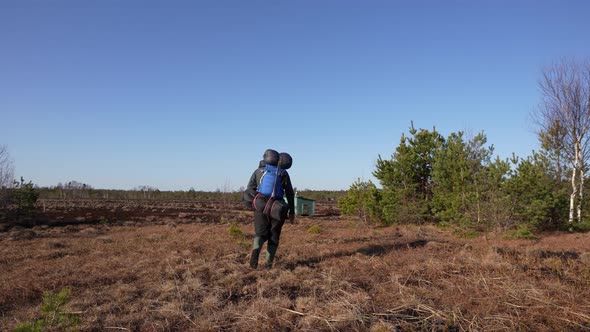 Photographer with Camping Backpack Walking in the Swamp to Found Wild Birds and Animals