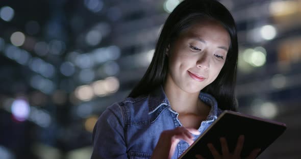 Woman use of tablet computer in city at night