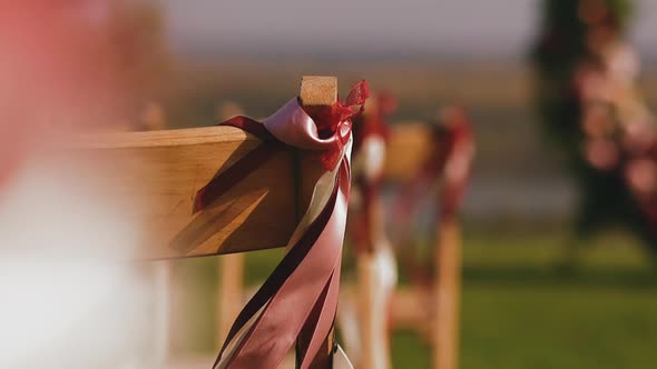 Wooden Chair Decorated with Pink Ribbon on Wedding Venue