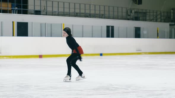 Small figure skater making toe loop inside ice arena