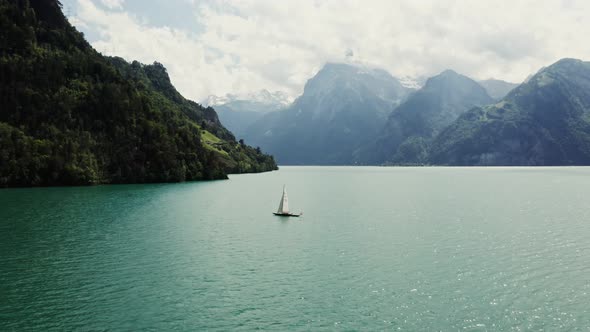 A Sailboat Floats on a Picturesque Lake at the Foot of the Alpine Mountains