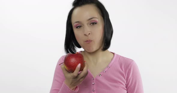 Young Beautiful Woman Eating Big, Fresh and Juicy Red Apple on White Background