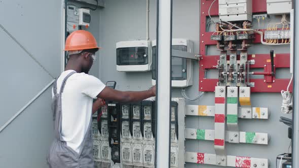 Man in Uniform Repairing Cables in Switchgear at Solar Farm