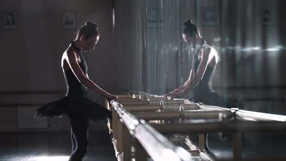 Young Woman Ballerina Walks to the Mirror and Starts Stretching