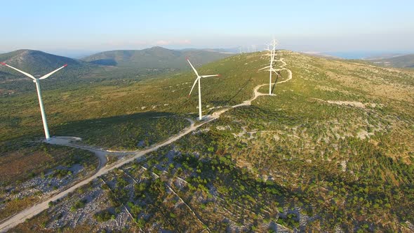Flying above elegant ecological wind turbines on green hills alt