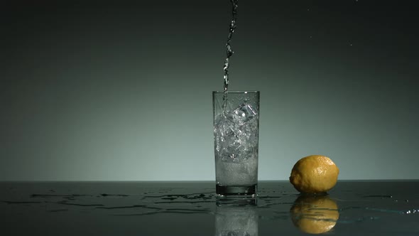 Carbonated liquid pouring into glass filled with ice 