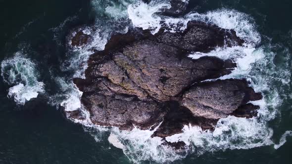 A birds-eye drone video looking down towards some large rocks above the ocean. Located in Tofino, Va