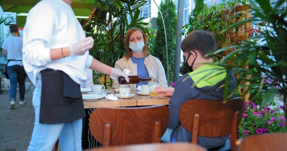 Waitress in Sterile Gloves Pours Juice Into Boy Glass