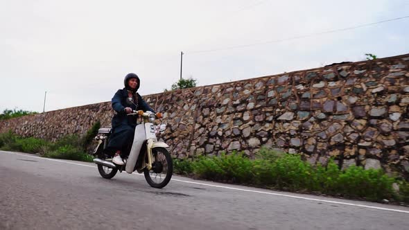 Young Caucasian Woman With Overcoat Riding White Moped Motor Scooter On Countryside Road. Side track