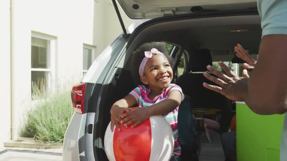 Happy african american family packing car with beach balls on holiday