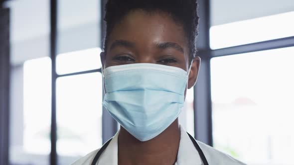 Portrait of african american female doctor wearing face mask looking at camera